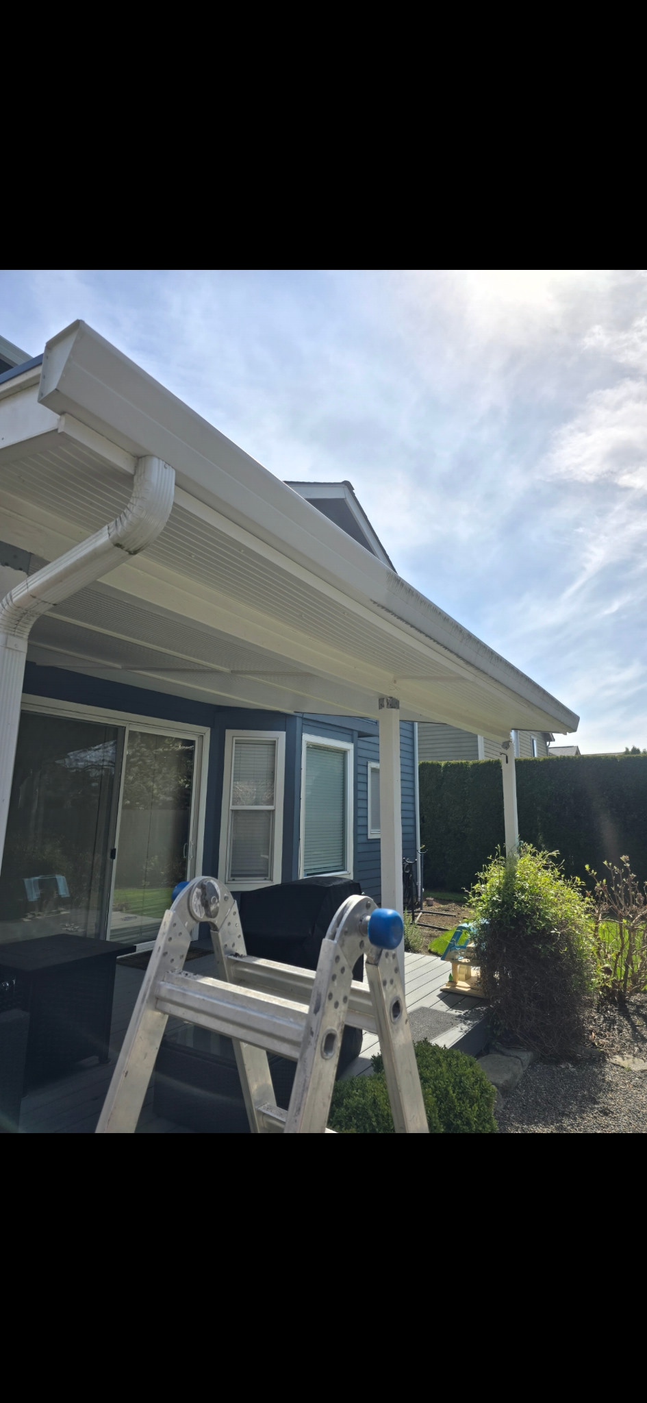 Same patio cover from another angle; near-left fascia is cleaner, with staining still visible farther along.